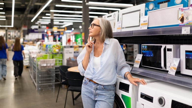 Woman looking thoughtfully beside display of appliances