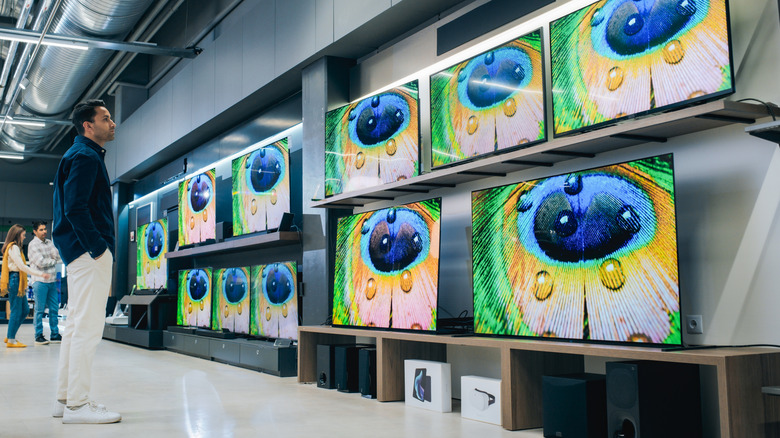 A person looking at a variety of modern smart TV sets with high quality resolution displays and vivid color transmission