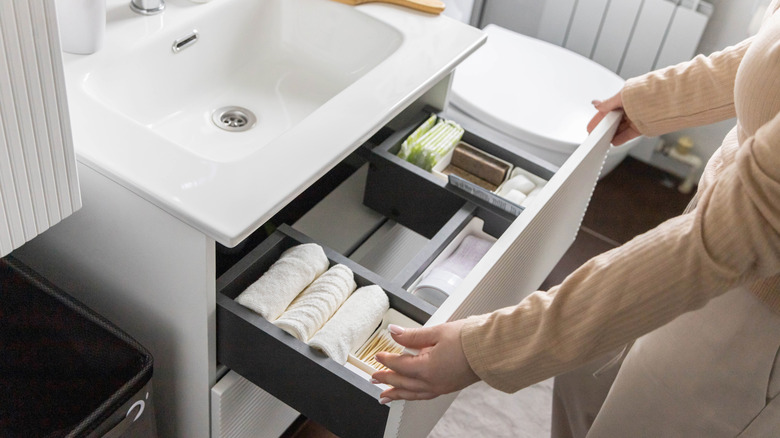 A person opening an organized drawer under a sink