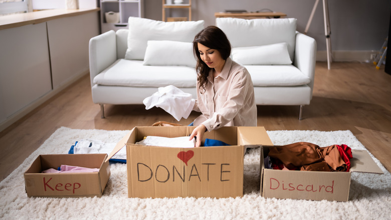 A person sorting items into keep, donate and discard boxes