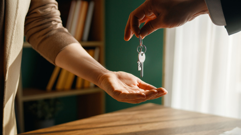 A person wearing a suit handing over keys to another person
