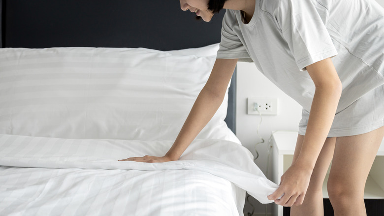 Person smoothing blanket on bed