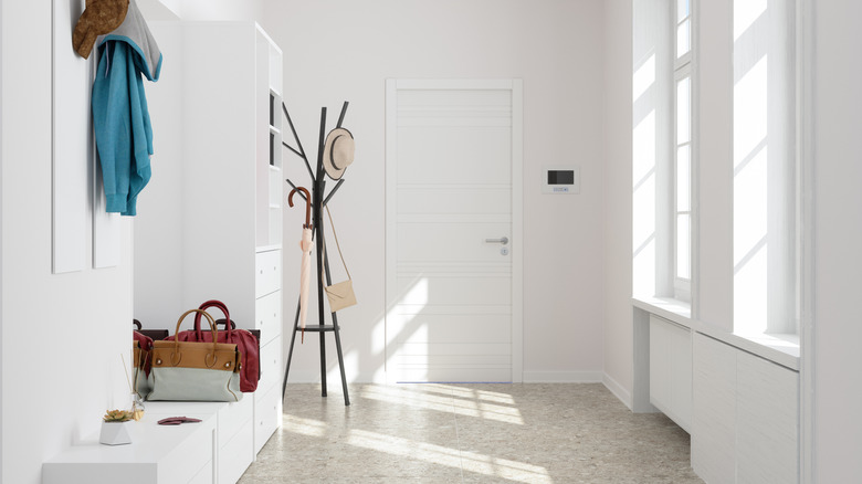 All white entryway with drawers, coat hanger, and shelves with purses