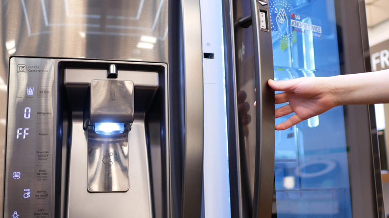 Person holding handle on refrigerator in an appliance store