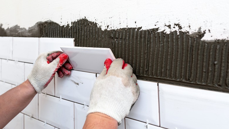 contractor placing tiles on wall