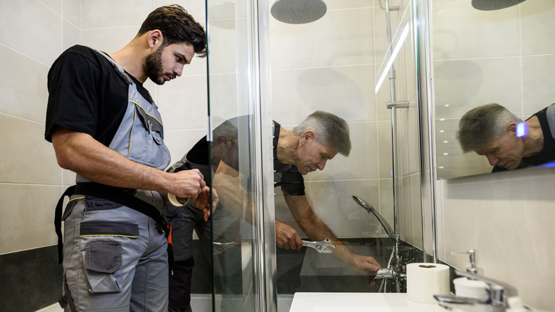 Two plumbers installing bathtub