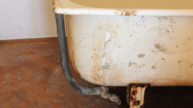 An old rusty bathtub sitting on a wood floor