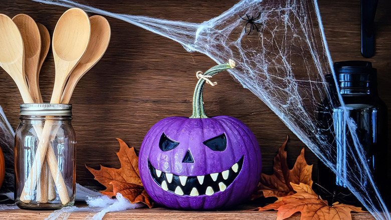 Purple Halloween pumpkin on a shelf that's decorated for the holiday