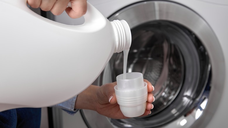 Person pouring liquid laundry detergent