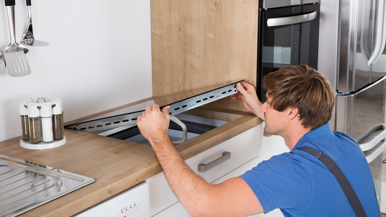 person lifting an induction stovetop from the counter