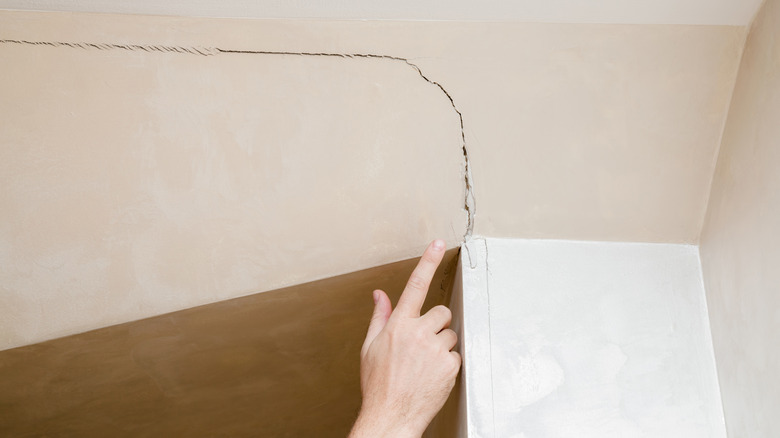 someone pointing at cracked wall