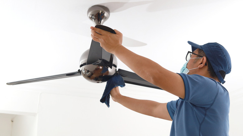 Man wiping down fan blades with a microfiber cloth