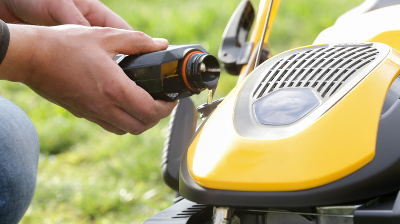 Person adding oil to a lawn mower