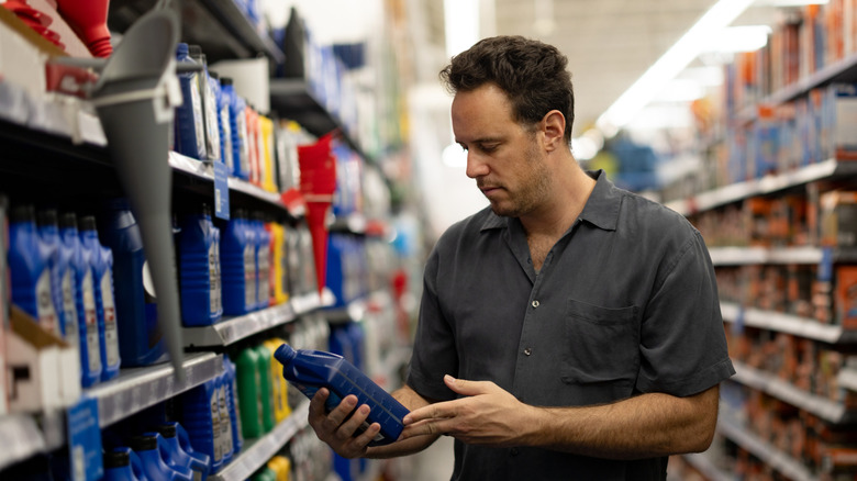 Man holding a bottle of motor oil in a store