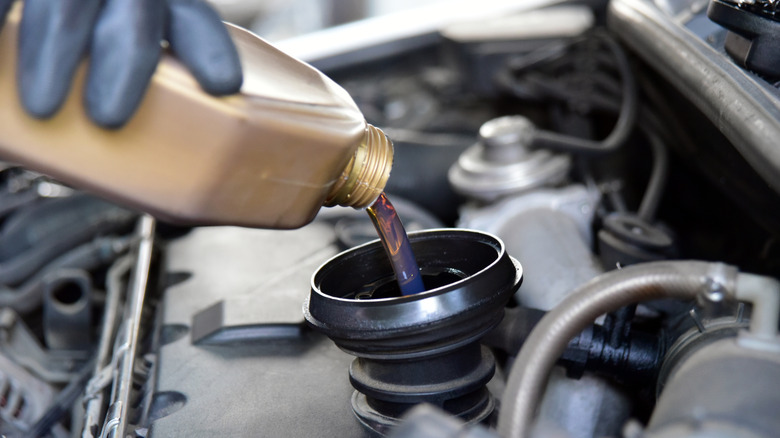 Person adding oil to a motor vehicle engine