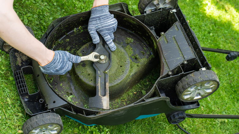 Gloved hands installing a lawn mower's blade
