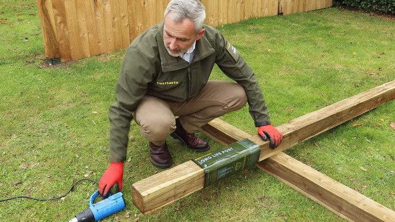 Man applying waterproof sleeve to a fence post