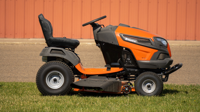 An orange riding mower sitting outside on a freshly cut lawn