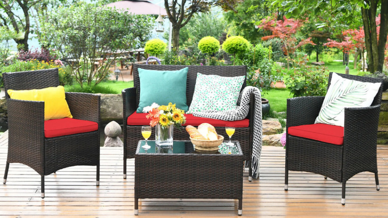 A rattan patio set with red cushions in a backyard