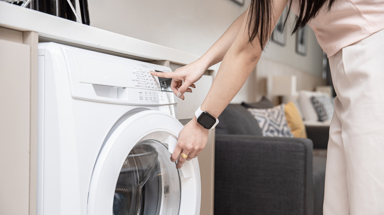 Person loads a washing machine, making sure to not add any dry-clean only items.