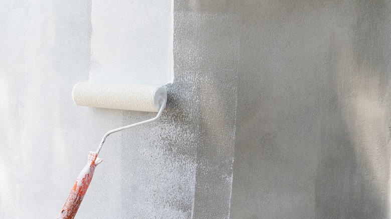 Painting gray wall with white paint on roller
