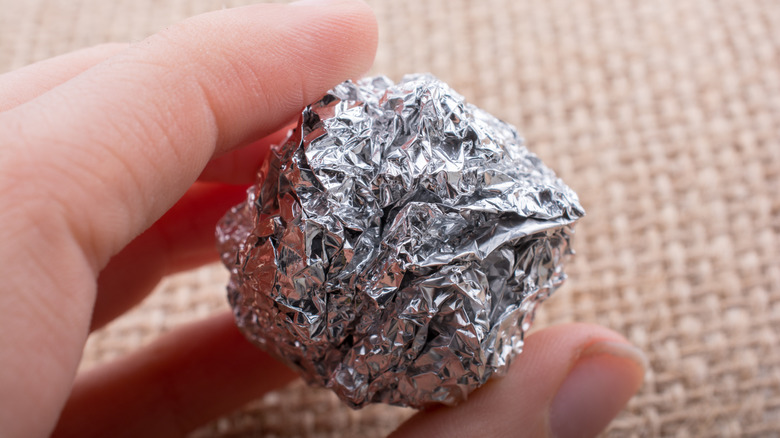 Someone holding aluminum foil ball