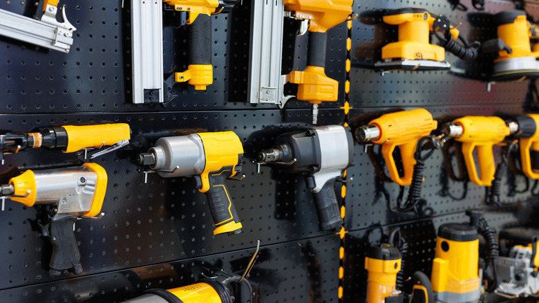A series of yellow and black cordless screwdrivers mounted on a wall