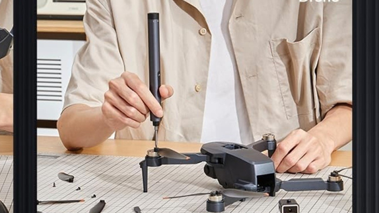 Person using electric screwdriver on a drone