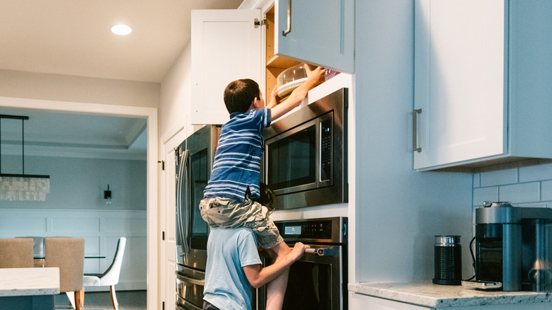 boy reaching high kitchen cabinet