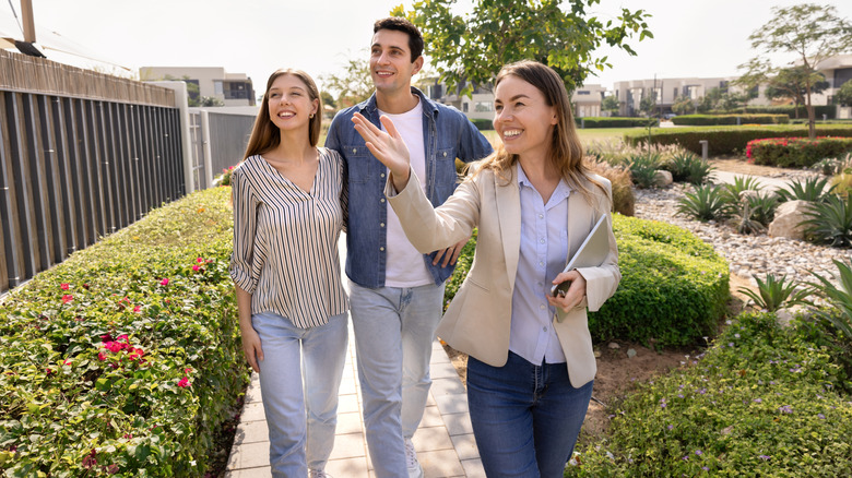 A female real estate agent showing a couple around the neighborhood of a house