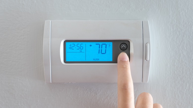 Woman adjusts wall thermostat