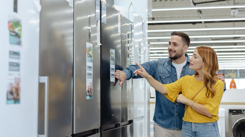 A man and woman shopping for a new fridge freezer in a store