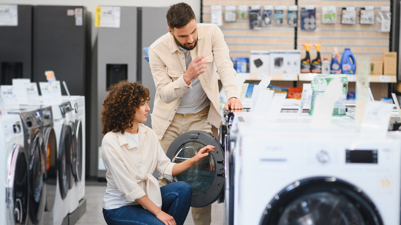 A couple comparing washing machines in a store