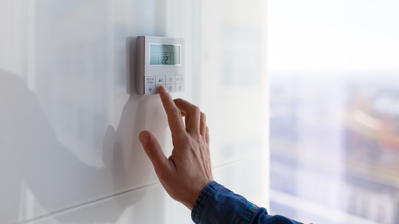 Person adjusting a thermostat