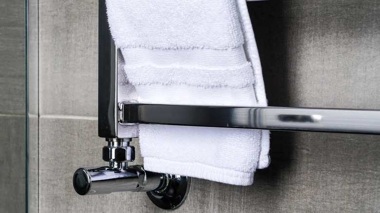 A white towel with a dobby border hanging on a metal bar.