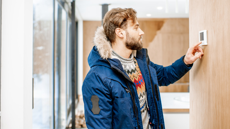 Man adjusting programmable thermostat