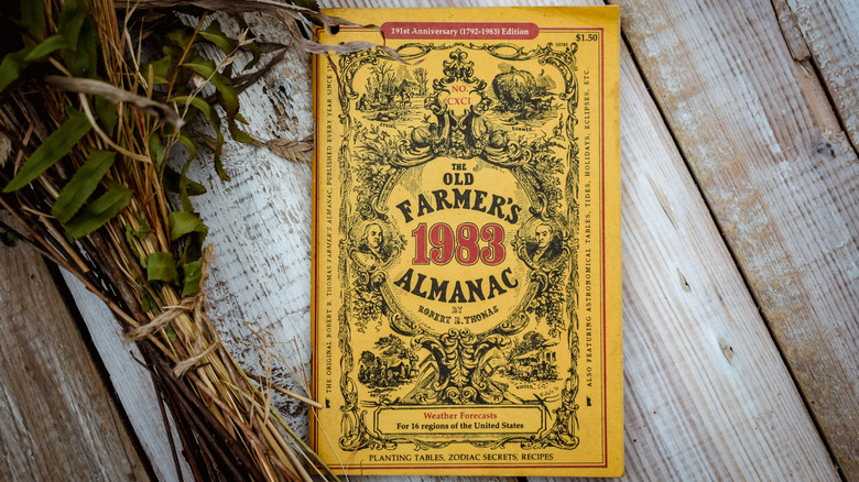 An Old Farmer's Almanac on a wooden table with plants bound in twine next to it