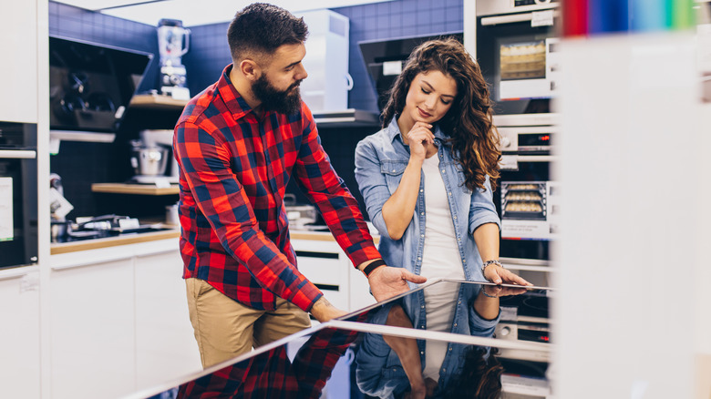 Couple looking at stoves in appliance store