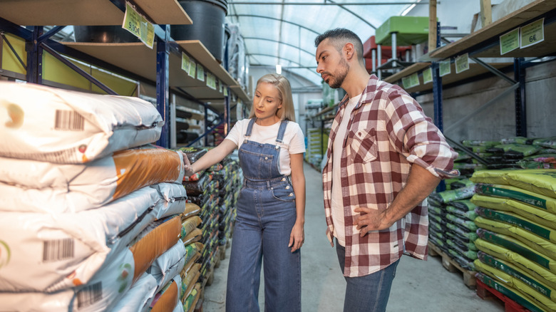 Couple looking at bags of soil in a garden center