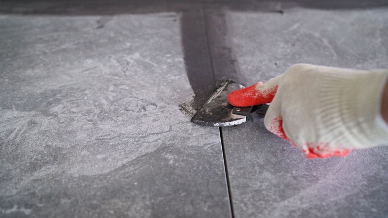 person wearing gloves applying grout between tiles