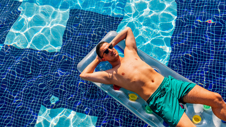 man laying on inflatable in pool