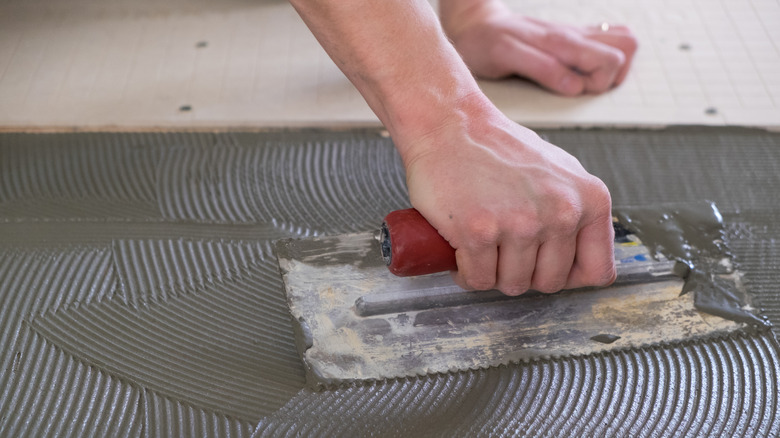 person using mortar and a trowel to lay tile