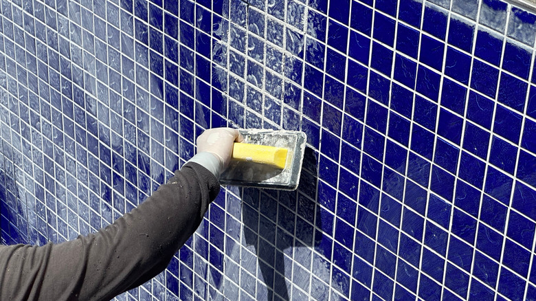 worker grouting blue pool tiles