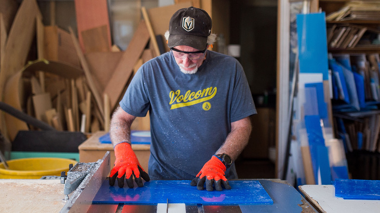 man cutting blue plexiglass