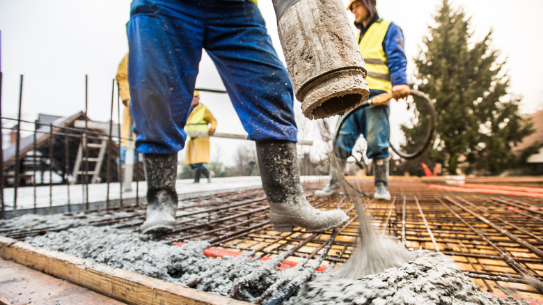 Contractors pouring concrete over rebar on a cold day in winter