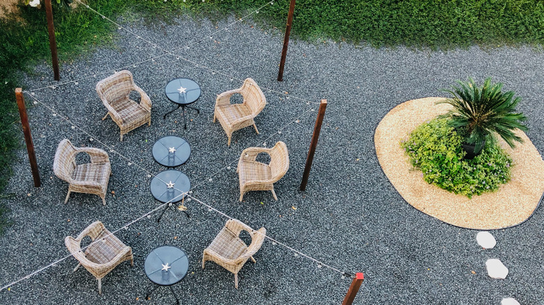 Gravel patio with chairs, tables, lights, and plants