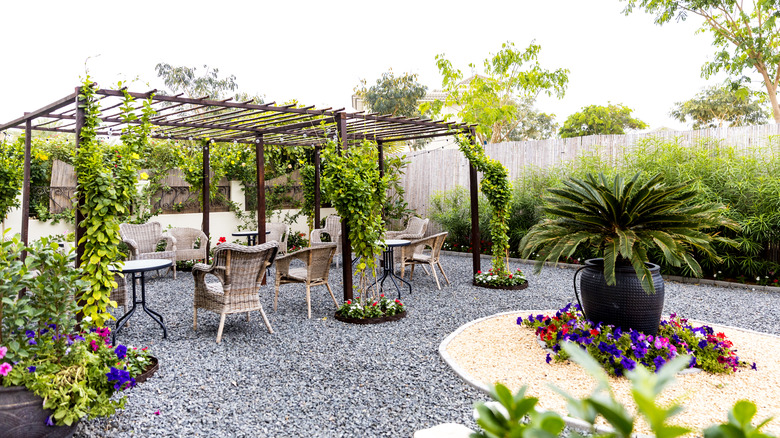 Pea gravel patio with pergola, tables, chairs, and plants