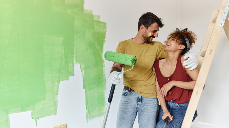 Couple painting the walls green