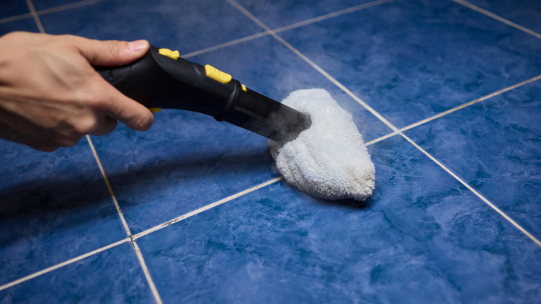 Hand using steam mop attachment on tile
