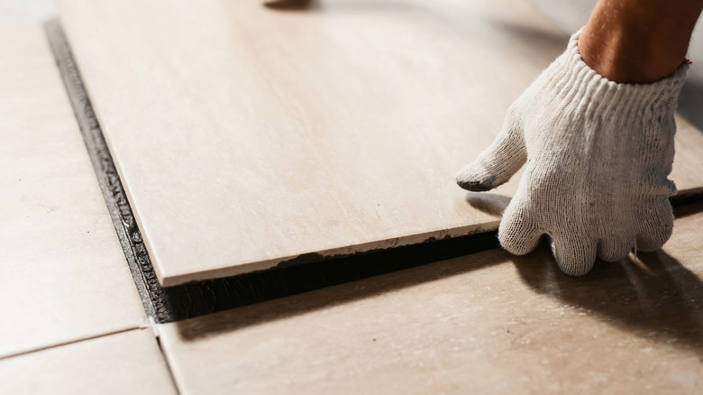 Close up of person installing ceramic tile flooring